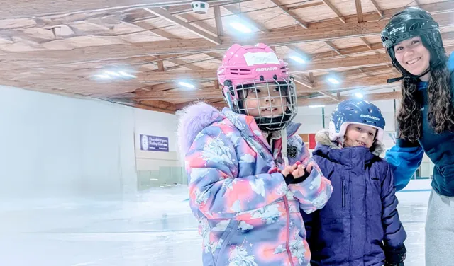 skate instructor with 3 young girls skating on the indoor ice rink