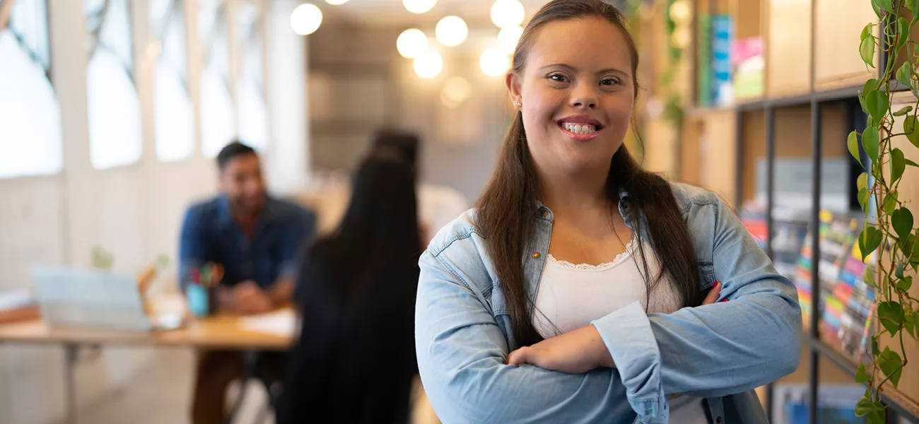 A young woman with disabilities smiling with her arms crossed