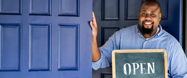 A person holding a sign that says "OPEN".