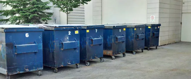 A group of blue waste bins lined up in a row.