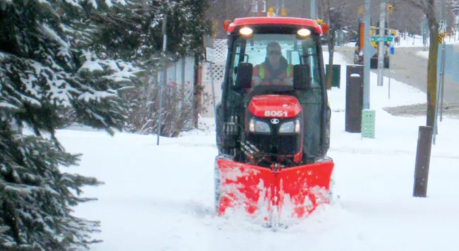 Snow plow removing snow from sidewalk