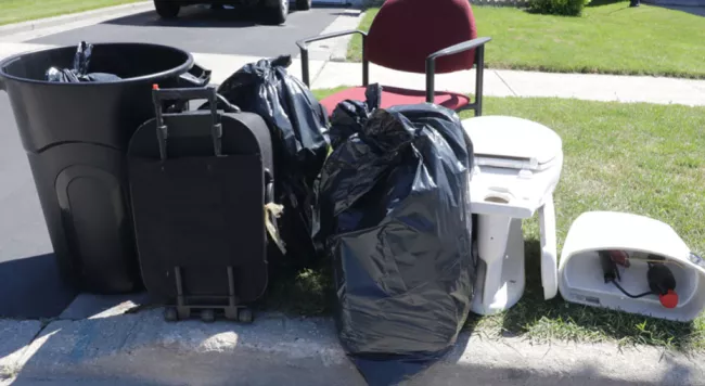 garbage bags, toilet, chair at the curb