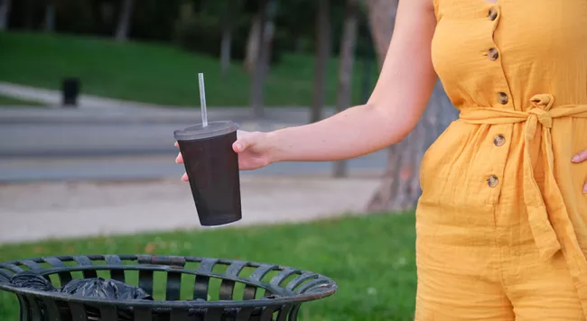 someone throwing a cup into the garbage