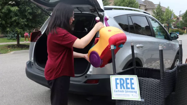 a woman loading a children's toy into a car