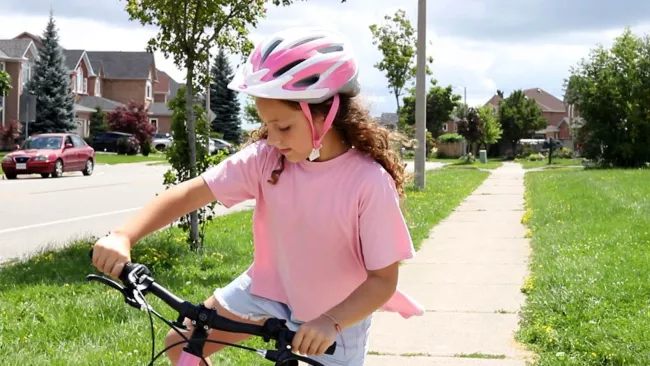 Little girl getting on her bike