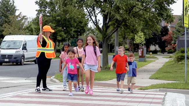 Kids crossing the street with a school crossing guard