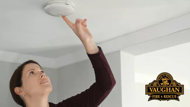 A woman testing her smoke alarm