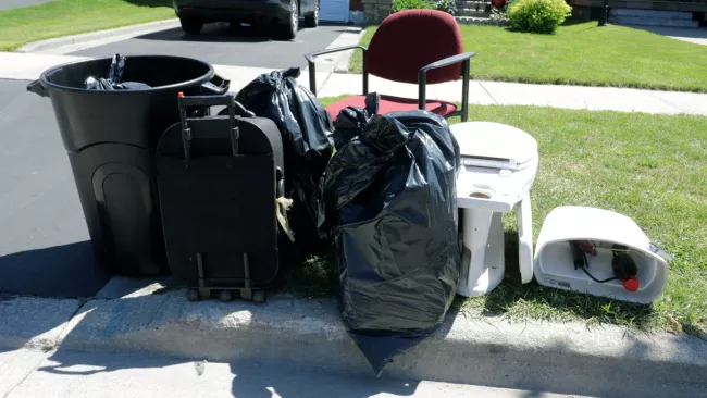 bags, a chair and toilet at the curb