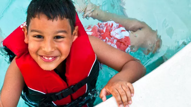 A child in a lifejacket in an indoor pool. 