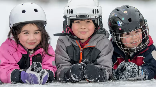 Three kids with helmets on the ice