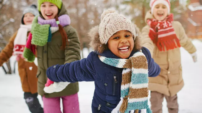 A group of kids playing outside in the snow