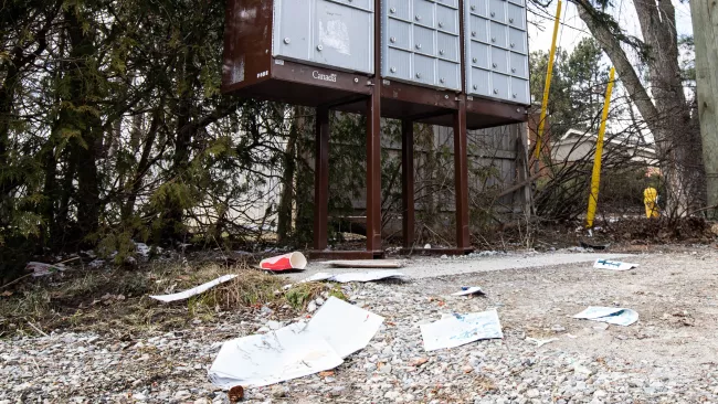 litter on the ground beside a Canada Post box