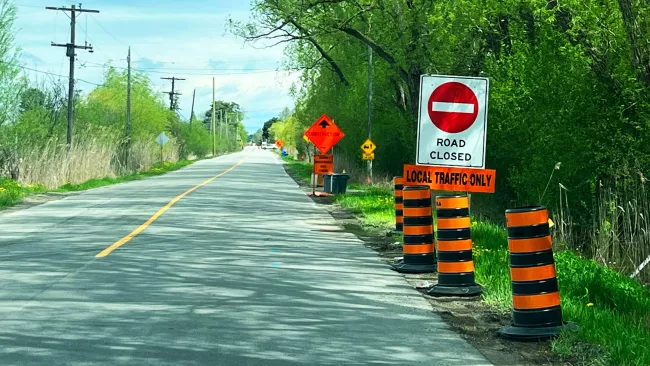 an empty road with orange pylons and a road closed sign