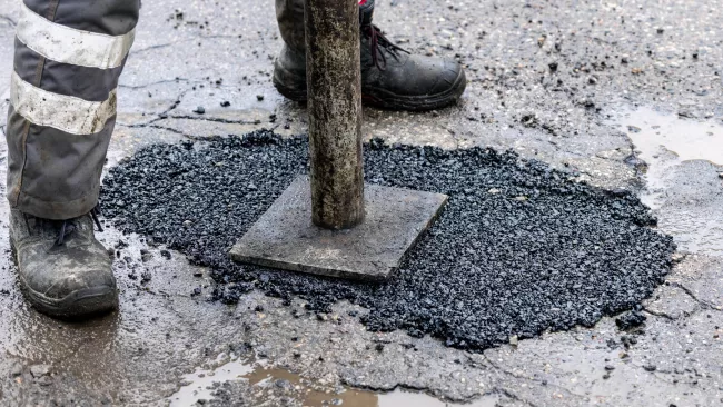 close up of a pot hole getting repaired. 