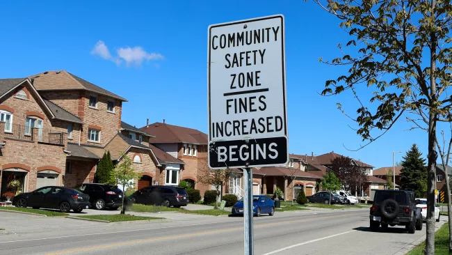 A road sign that says "COMMUNITY SAFETY ZONES FINES INCREASED BEGINS"