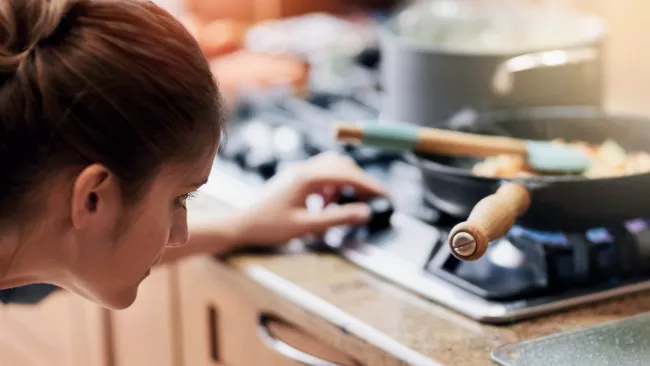 Someone cooking at a gas stove and checking the burner