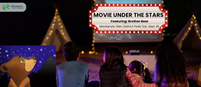 A family watching a movie outdoors during the night