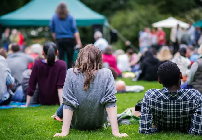 A group of people sitting on grass