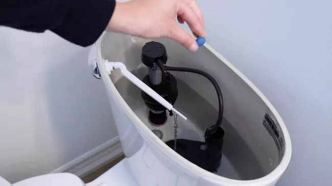 someone dropping a dye tablet into a toilet tank