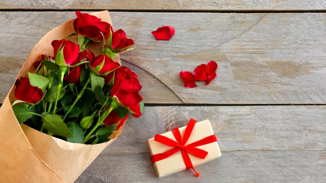 a bouquet of red roses and a gift box