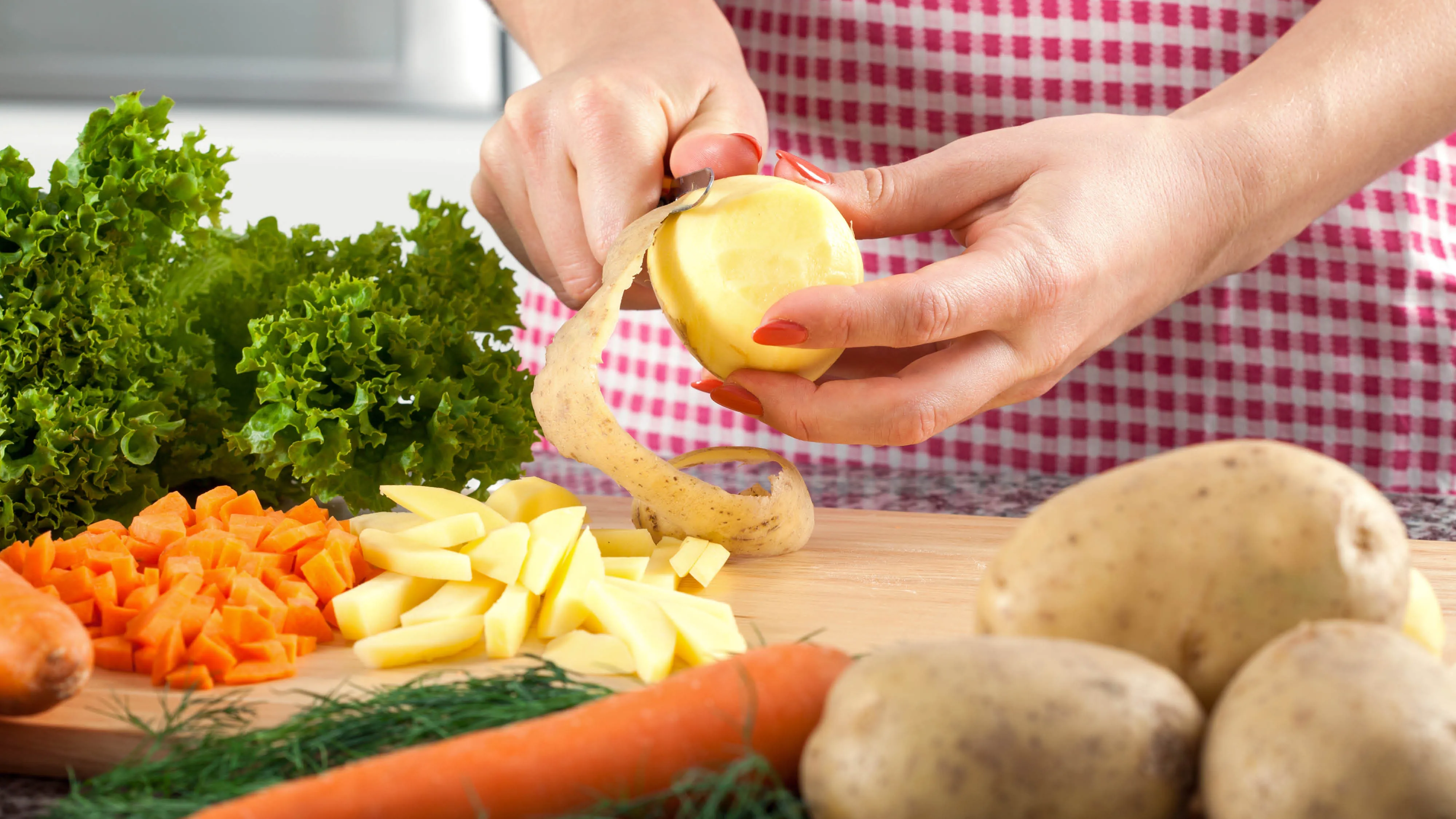 someone peeling a potato on a cutting board