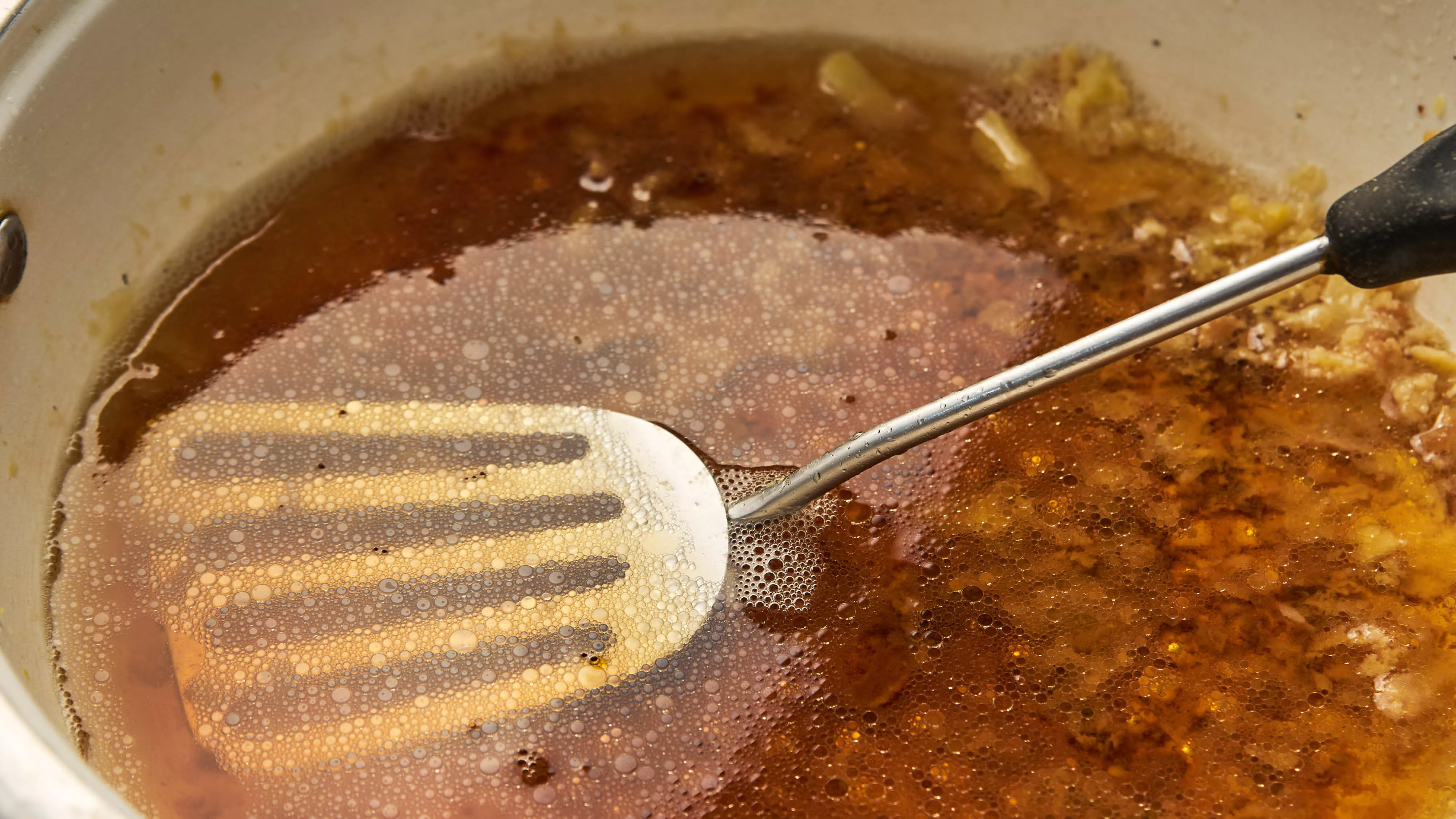 a pan with oil and a spatula in it